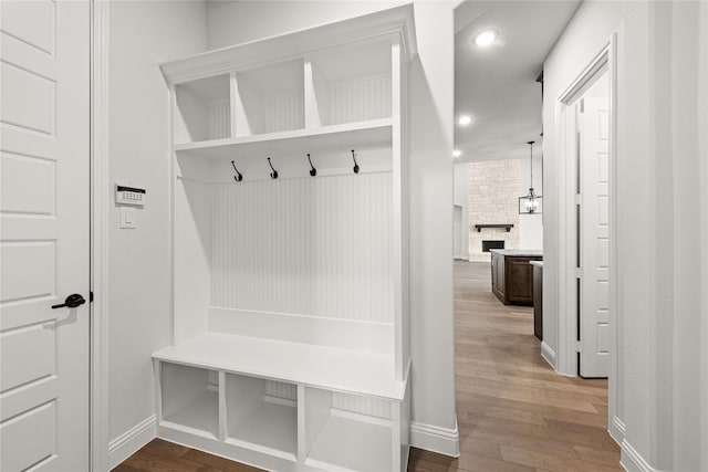 mudroom featuring wood-type flooring and a fireplace