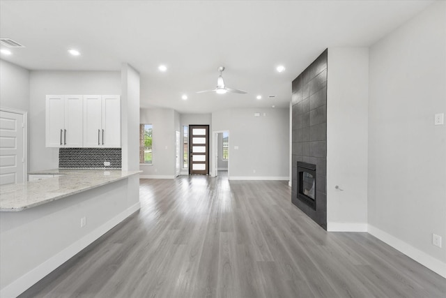 unfurnished living room featuring ceiling fan, a tile fireplace, and light hardwood / wood-style flooring