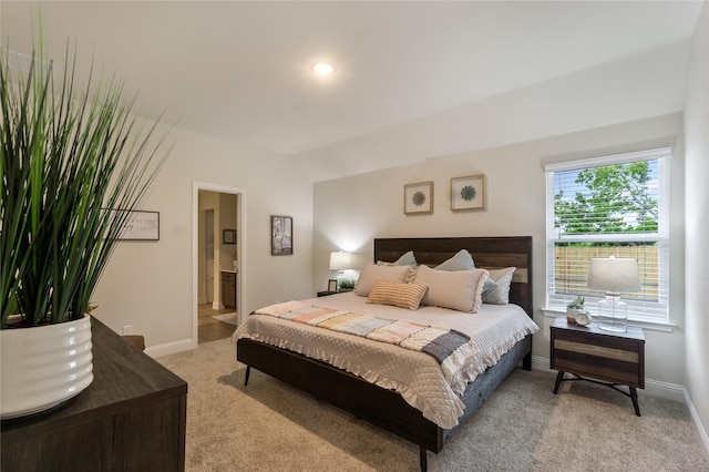 carpeted bedroom with ensuite bath and multiple windows