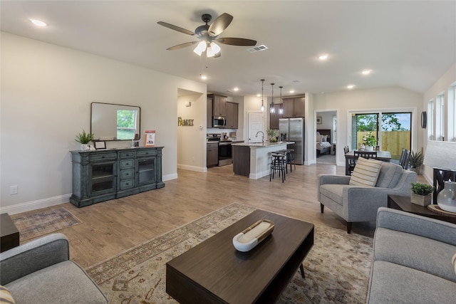 living room featuring ceiling fan, light hardwood / wood-style flooring, and sink