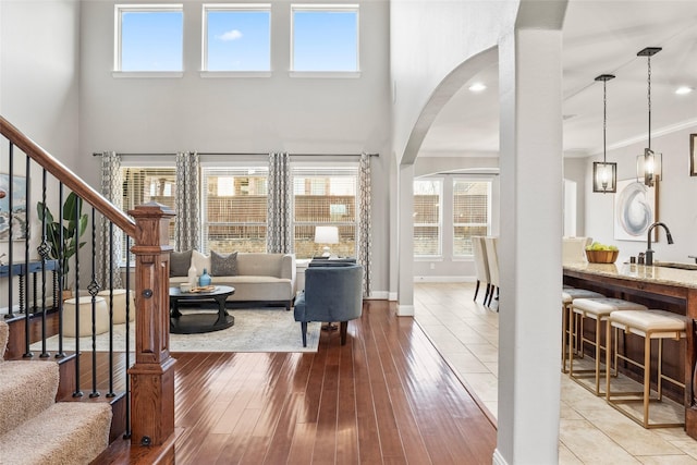 living room with light wood-type flooring, ornamental molding, sink, and a wealth of natural light