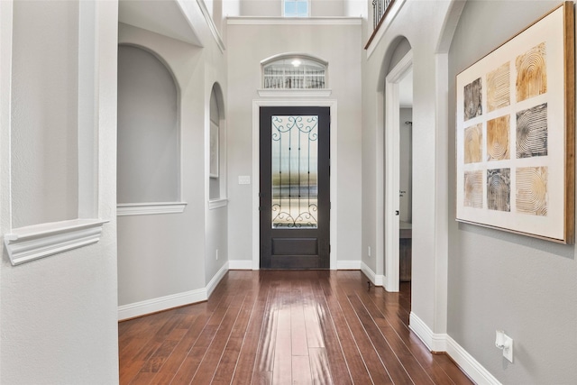 entrance foyer featuring a towering ceiling and dark wood-type flooring