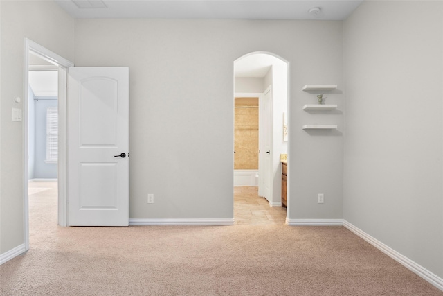 unfurnished bedroom with light colored carpet and ensuite bathroom