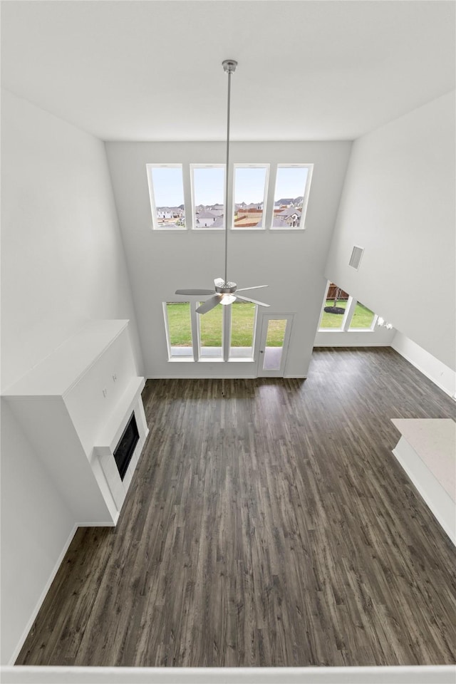 unfurnished living room featuring ceiling fan and dark hardwood / wood-style flooring