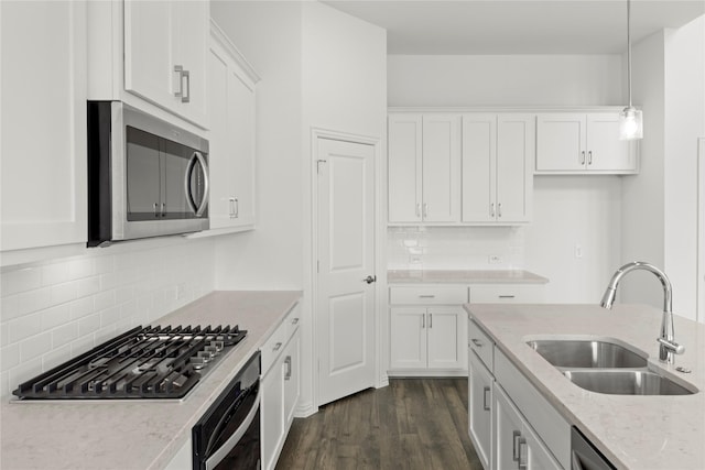 kitchen with sink, hanging light fixtures, stainless steel appliances, light stone counters, and white cabinets