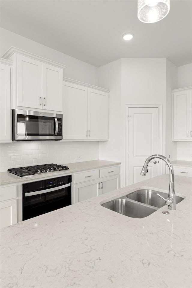 kitchen featuring white cabinets, stainless steel appliances, light stone counters, and sink