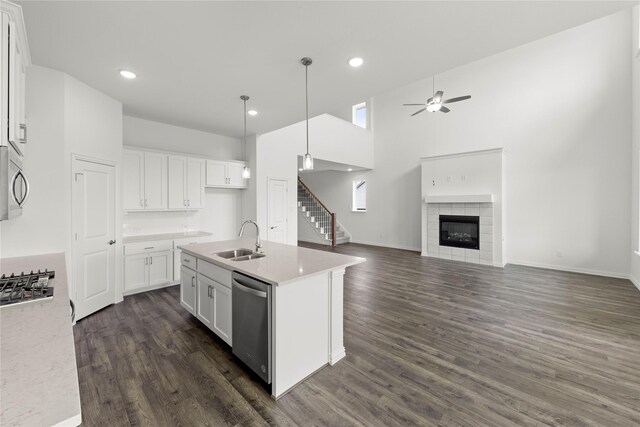 kitchen featuring sink, stainless steel dishwasher, an island with sink, white cabinetry, and a tiled fireplace