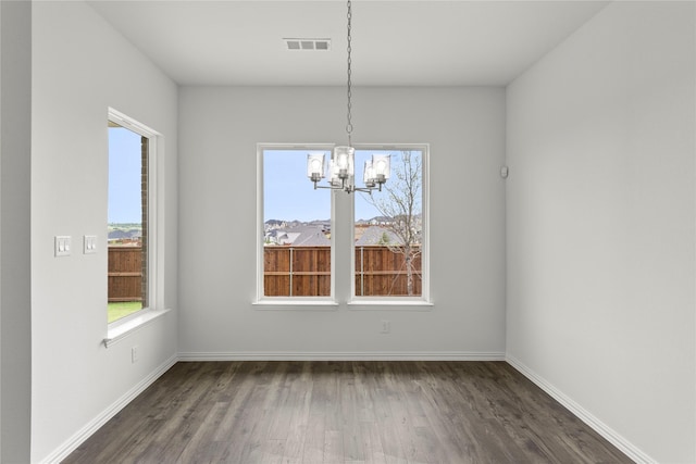 unfurnished dining area with dark wood-type flooring and a notable chandelier