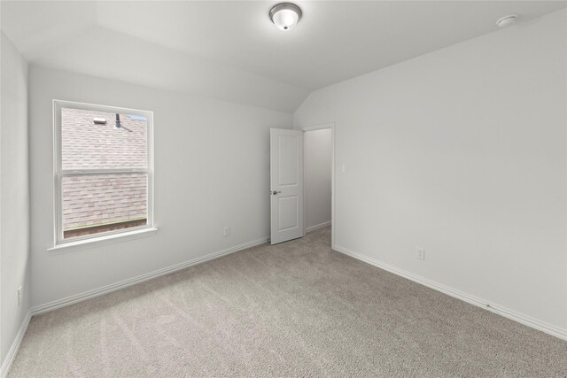 spare room with light carpet and lofted ceiling