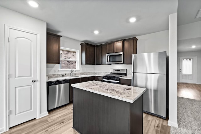 kitchen with dark brown cabinetry, sink, stainless steel appliances, light hardwood / wood-style flooring, and a kitchen island