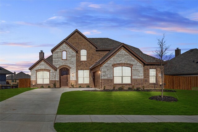 french country inspired facade featuring a garage and a front yard