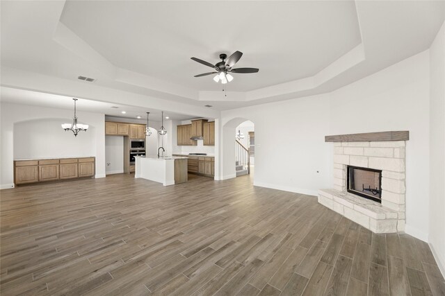 kitchen featuring a center island with sink, oven, gas stovetop, light stone countertops, and built in microwave