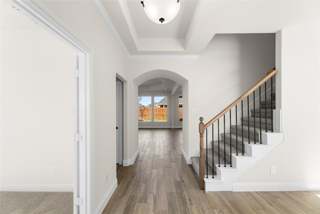 foyer with hardwood / wood-style flooring, ornamental molding, and a tray ceiling