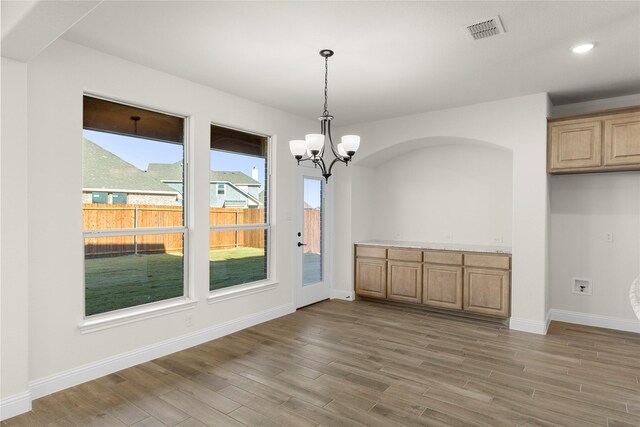 kitchen featuring sink, hardwood / wood-style flooring, decorative light fixtures, light stone counters, and stainless steel appliances