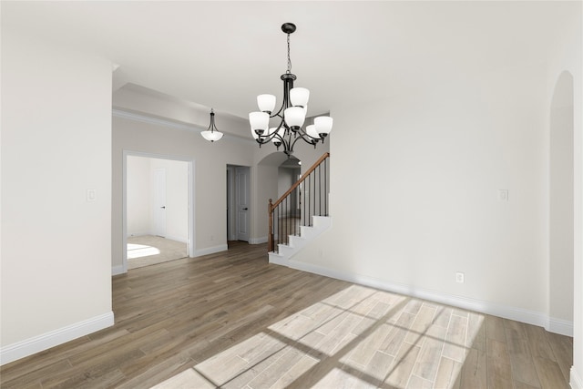 empty room with ornamental molding, light wood-type flooring, and a chandelier