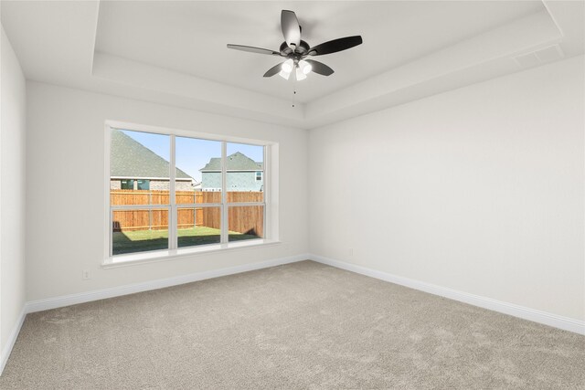 carpeted spare room featuring a raised ceiling and ceiling fan