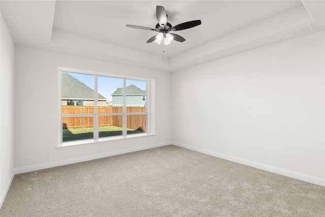 carpeted empty room featuring a raised ceiling and ceiling fan