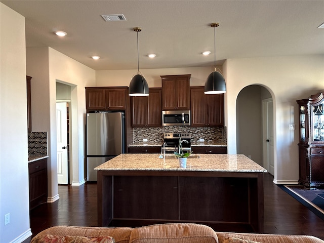 kitchen featuring sink, dark brown cabinets, hanging light fixtures, stainless steel appliances, and light stone countertops