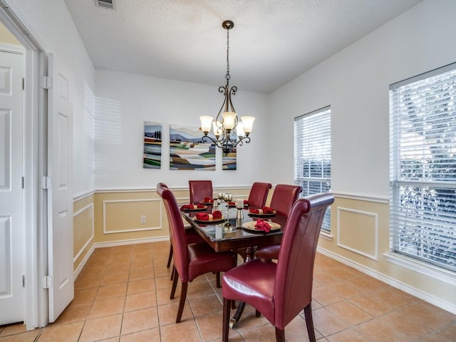 tiled dining room with a textured ceiling and an inviting chandelier