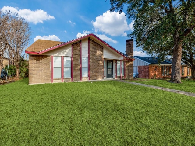 view of front of house with brick siding, a chimney, and a front lawn