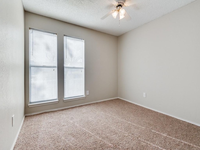 spare room with carpet flooring, a ceiling fan, baseboards, and a textured ceiling