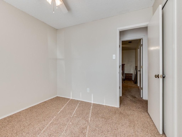 carpeted spare room with a textured ceiling and ceiling fan