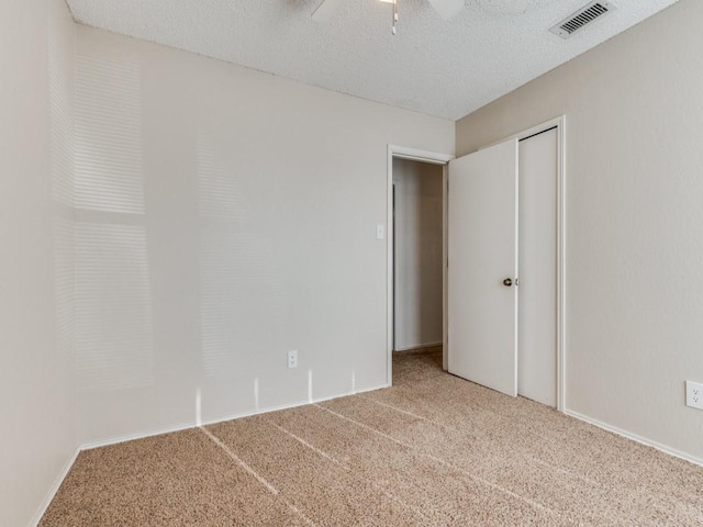 carpeted spare room featuring visible vents, a textured ceiling, and a ceiling fan