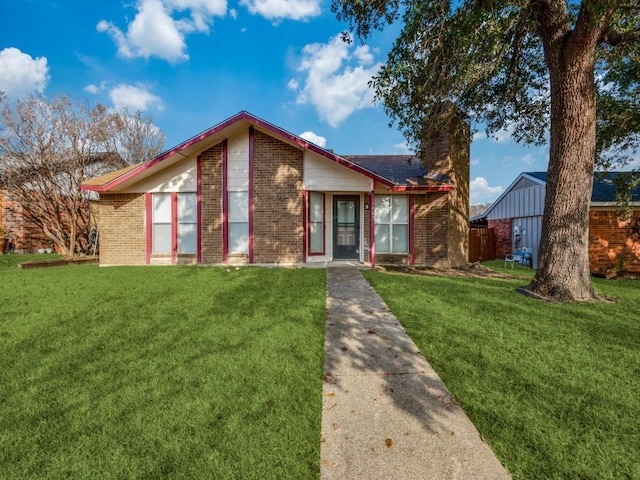 view of front of property with a chimney, a front lawn, and brick siding