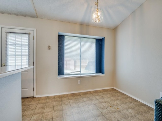 unfurnished dining area with a wealth of natural light, a notable chandelier, and baseboards