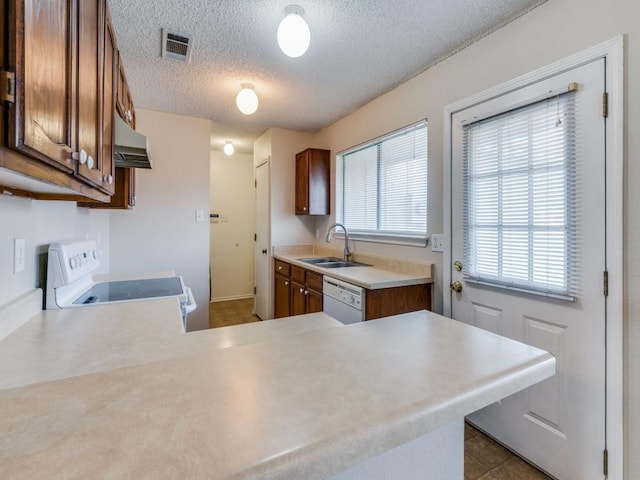 kitchen featuring white appliances, visible vents, a sink, light countertops, and under cabinet range hood