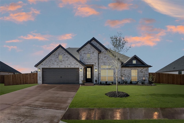 french provincial home featuring a garage and a yard