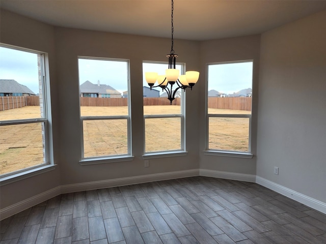 unfurnished dining area with dark wood-type flooring and a notable chandelier