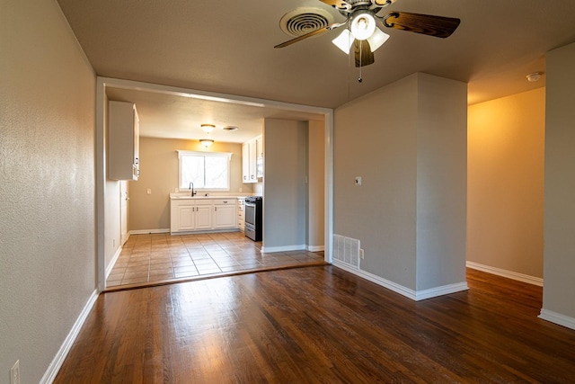 interior space featuring baseboards, visible vents, a sink, and wood finished floors