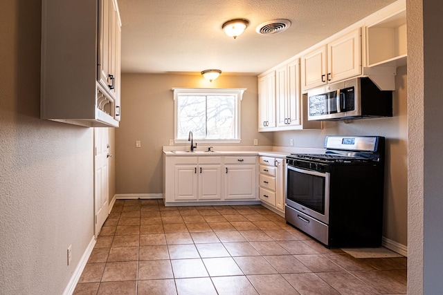 kitchen featuring stainless steel appliances, a sink, visible vents, baseboards, and open shelves