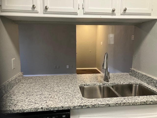 kitchen with light stone countertops, white cabinetry, and sink