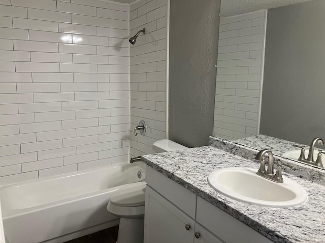 full bathroom featuring a textured ceiling, vanity, toilet, and tiled shower / bath