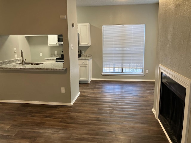 kitchen with white cabinetry, sink, light stone countertops, dark hardwood / wood-style floors, and stainless steel electric stove