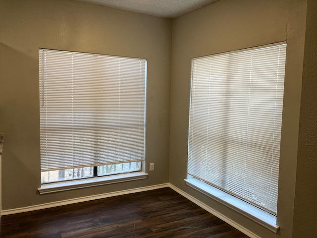 empty room with dark hardwood / wood-style flooring and a textured ceiling