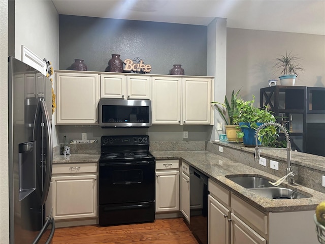 kitchen featuring sink, light stone counters, dark hardwood / wood-style flooring, kitchen peninsula, and black appliances