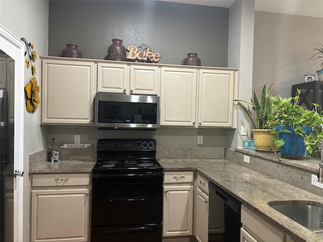 kitchen featuring black appliances, white cabinetry, light stone countertops, and sink