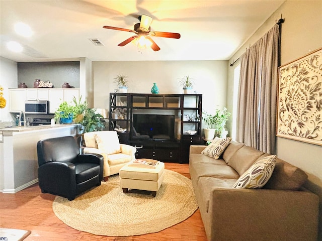 living room featuring ceiling fan, light hardwood / wood-style floors, and sink