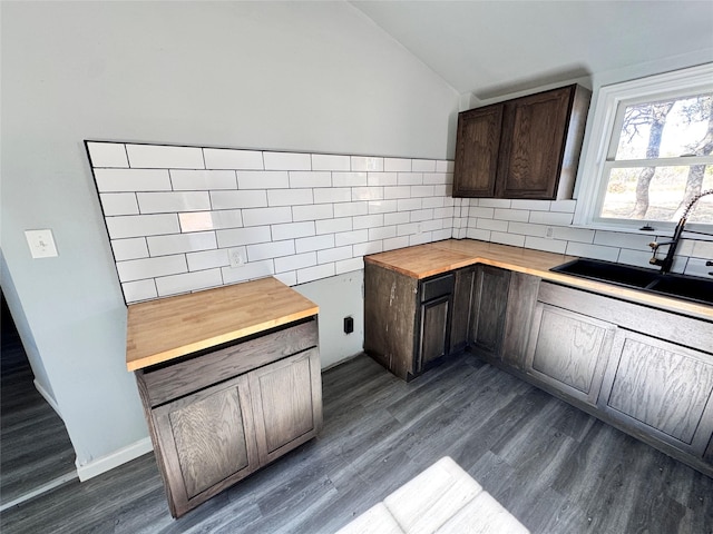 kitchen featuring butcher block counters, dark brown cabinetry, sink, dark hardwood / wood-style floors, and vaulted ceiling