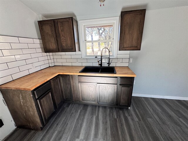 kitchen featuring wood counters, backsplash, sink, vaulted ceiling, and dark brown cabinetry