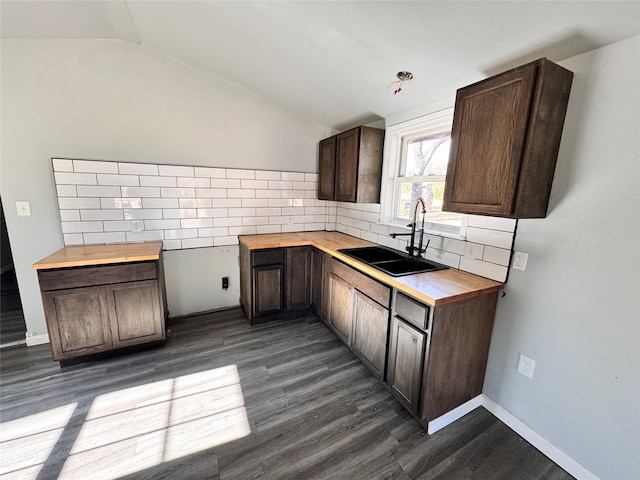 kitchen featuring lofted ceiling, butcher block countertops, sink, backsplash, and dark hardwood / wood-style floors