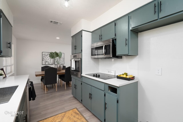 kitchen featuring backsplash, appliances with stainless steel finishes, and light hardwood / wood-style flooring