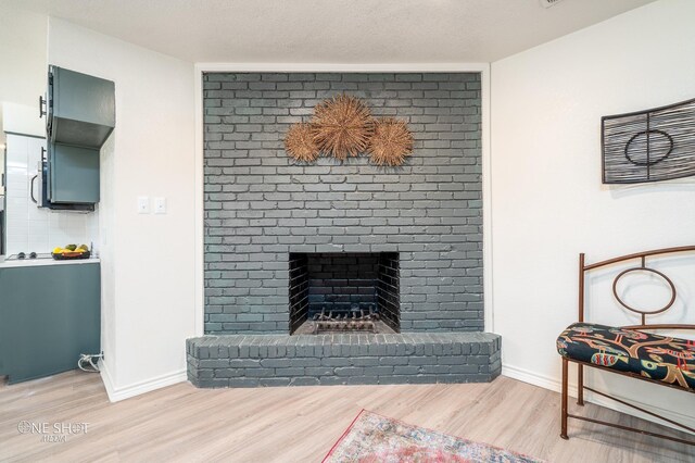 living room featuring a textured ceiling, light hardwood / wood-style floors, and a fireplace