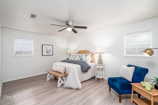 bedroom featuring ceiling fan, light hardwood / wood-style floors, and a textured ceiling