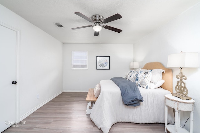 bedroom with a textured ceiling, hardwood / wood-style flooring, and ceiling fan