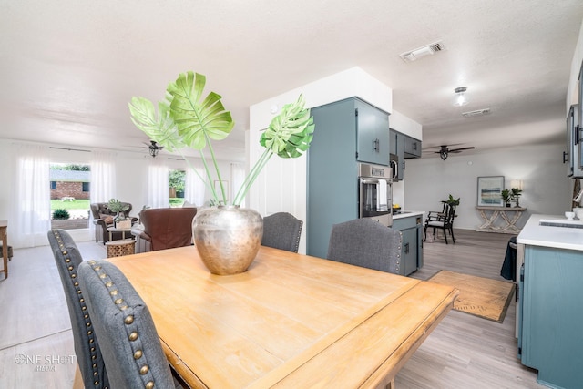 dining room featuring ceiling fan, sink, and light hardwood / wood-style flooring