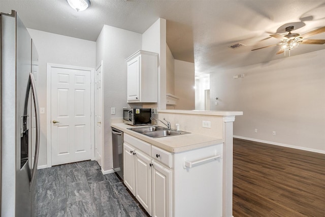 kitchen featuring sink, dark hardwood / wood-style floors, appliances with stainless steel finishes, white cabinetry, and kitchen peninsula